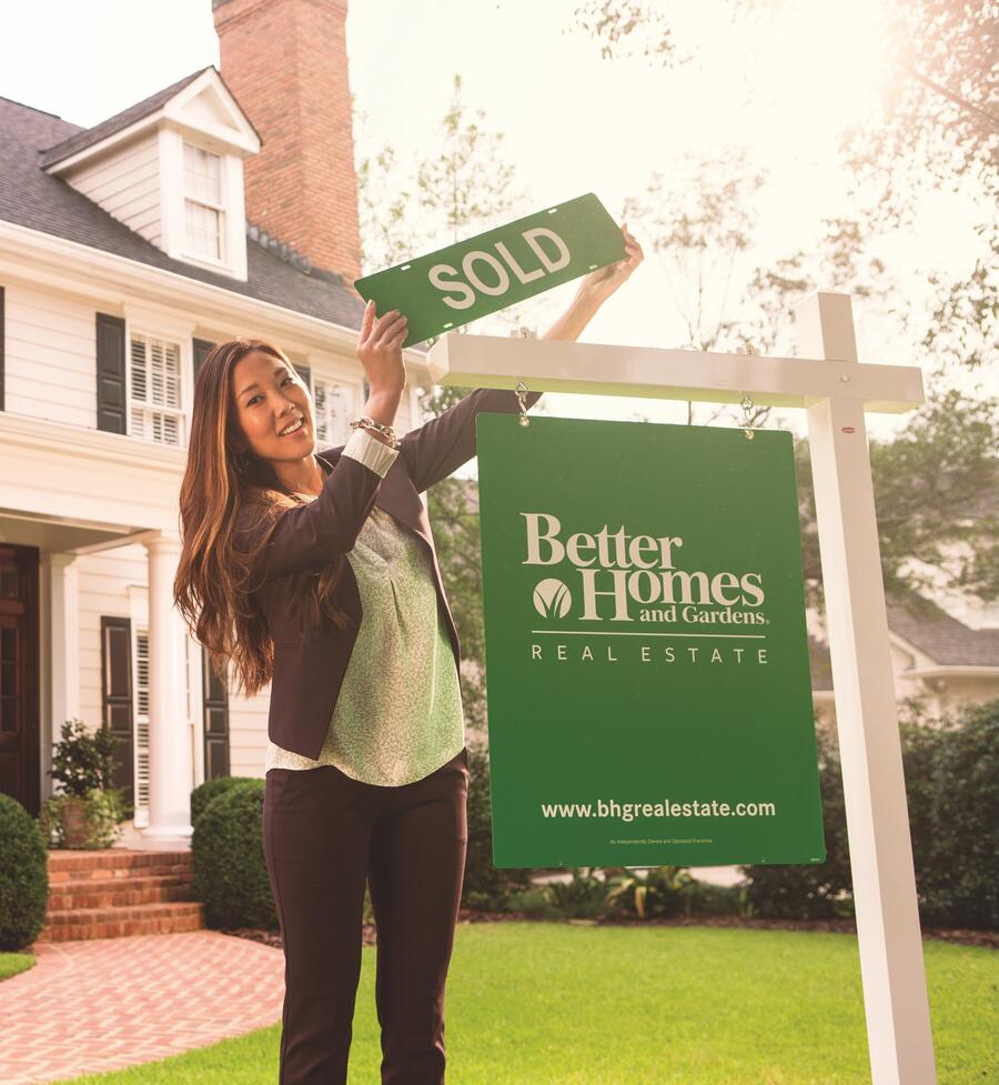 A 43° North agent hanging a SOLD rider on a Better Homes and Gardens Real Estate sign