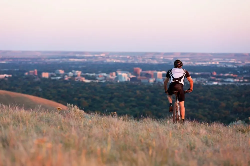 Man on mountain bike riding in the foothills, downtown Boise is visible in the distance