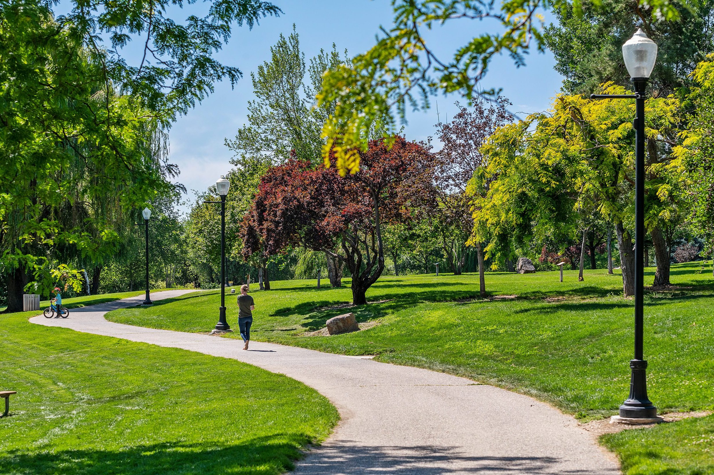 Curved walking path lined with street lamps, cutting through Indian Creek Park in Kuna Idaho