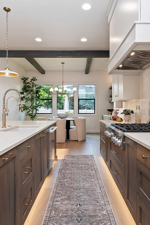 O2 Construction, Kitchen Island with Sink, Stove and Countertops, White Granite, White Pendant Light, Brown Ceiling Beams, Dining area
