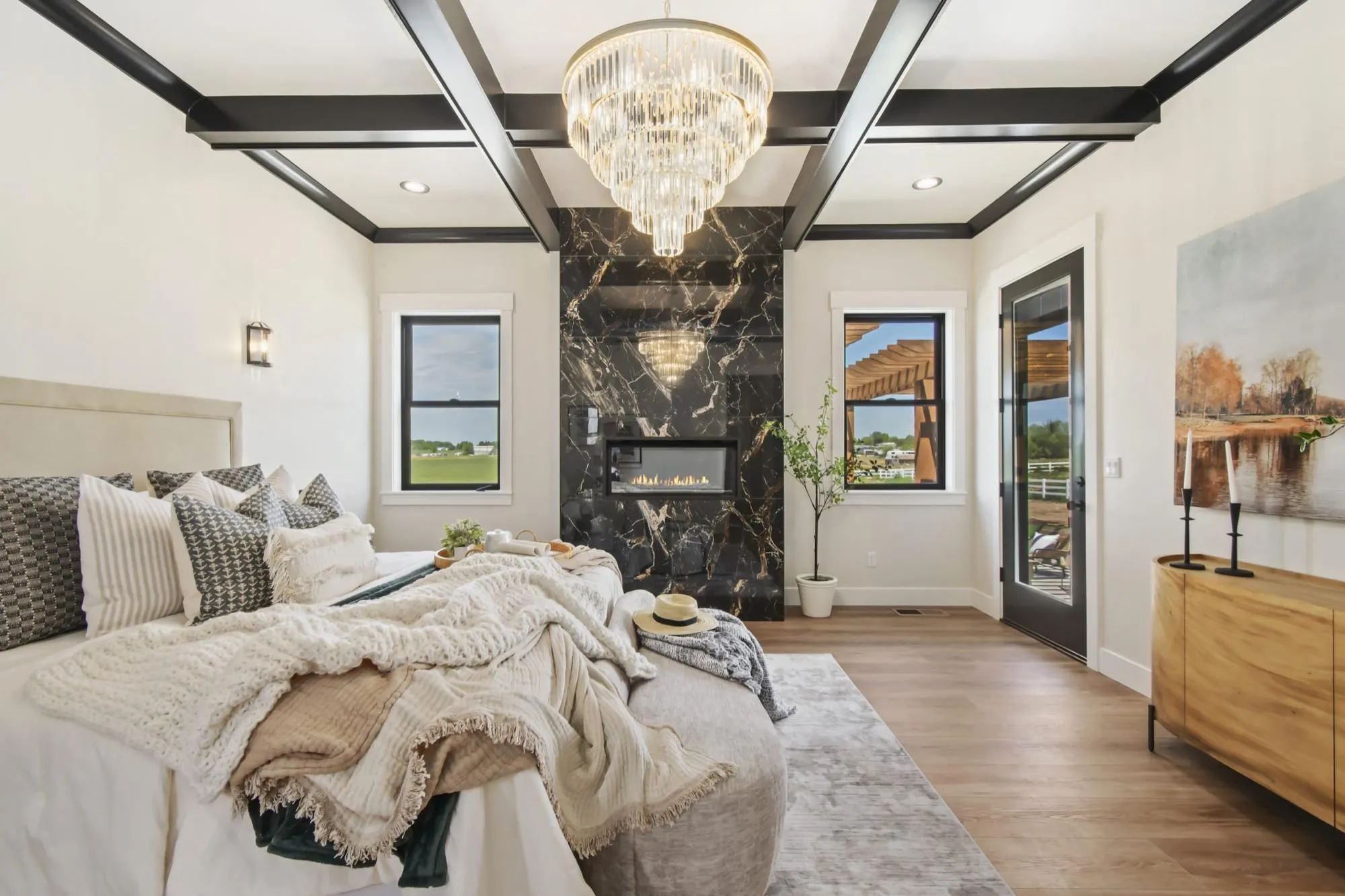 Primary bedroom with a chandelier and marble fireplace in a luxury home