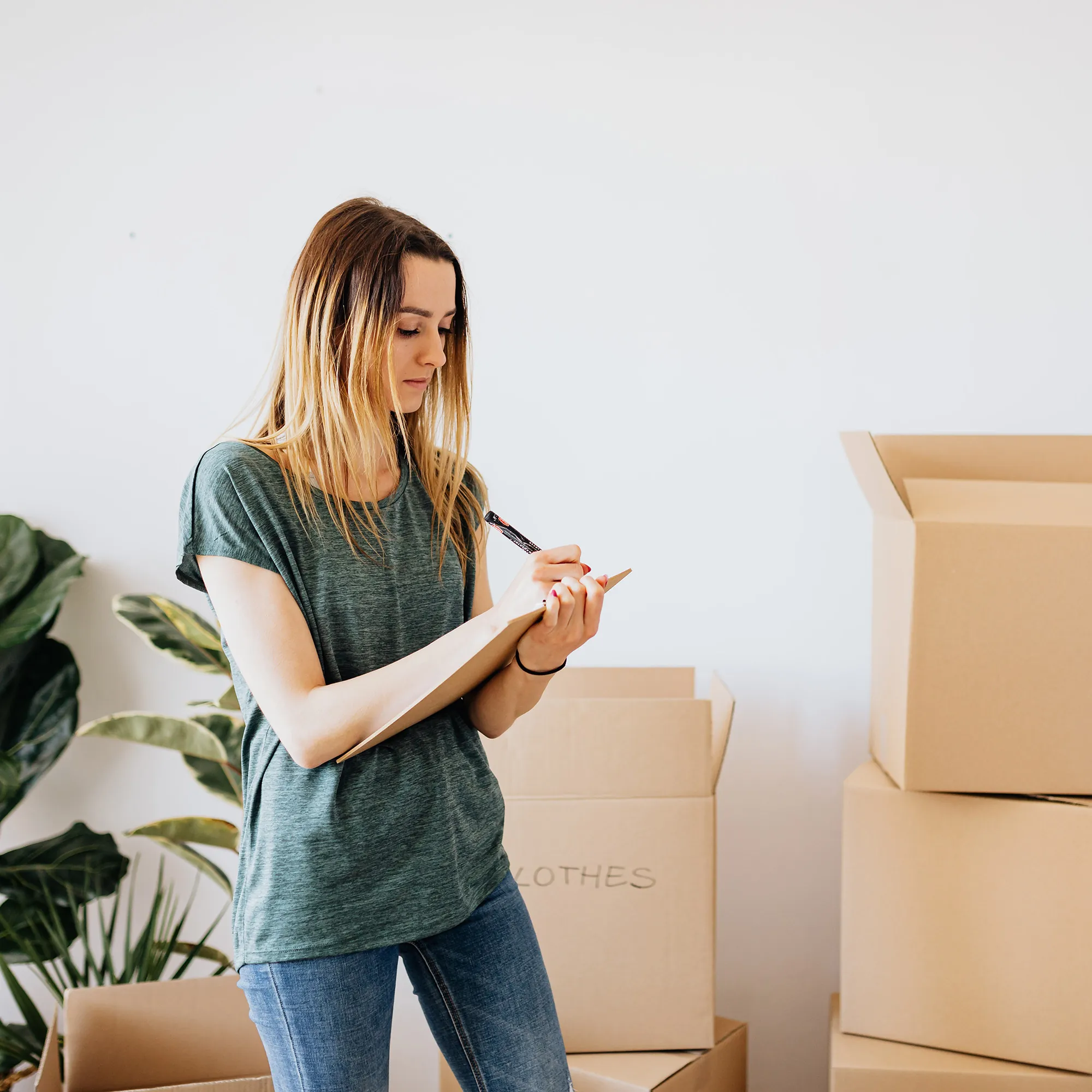 A homeowner planning her sale with a clipboard beside moving boxes