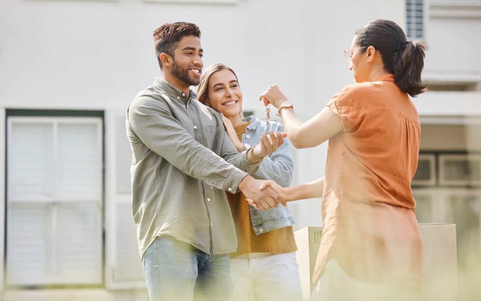 Homeowners shaking hands with their agent outside their home