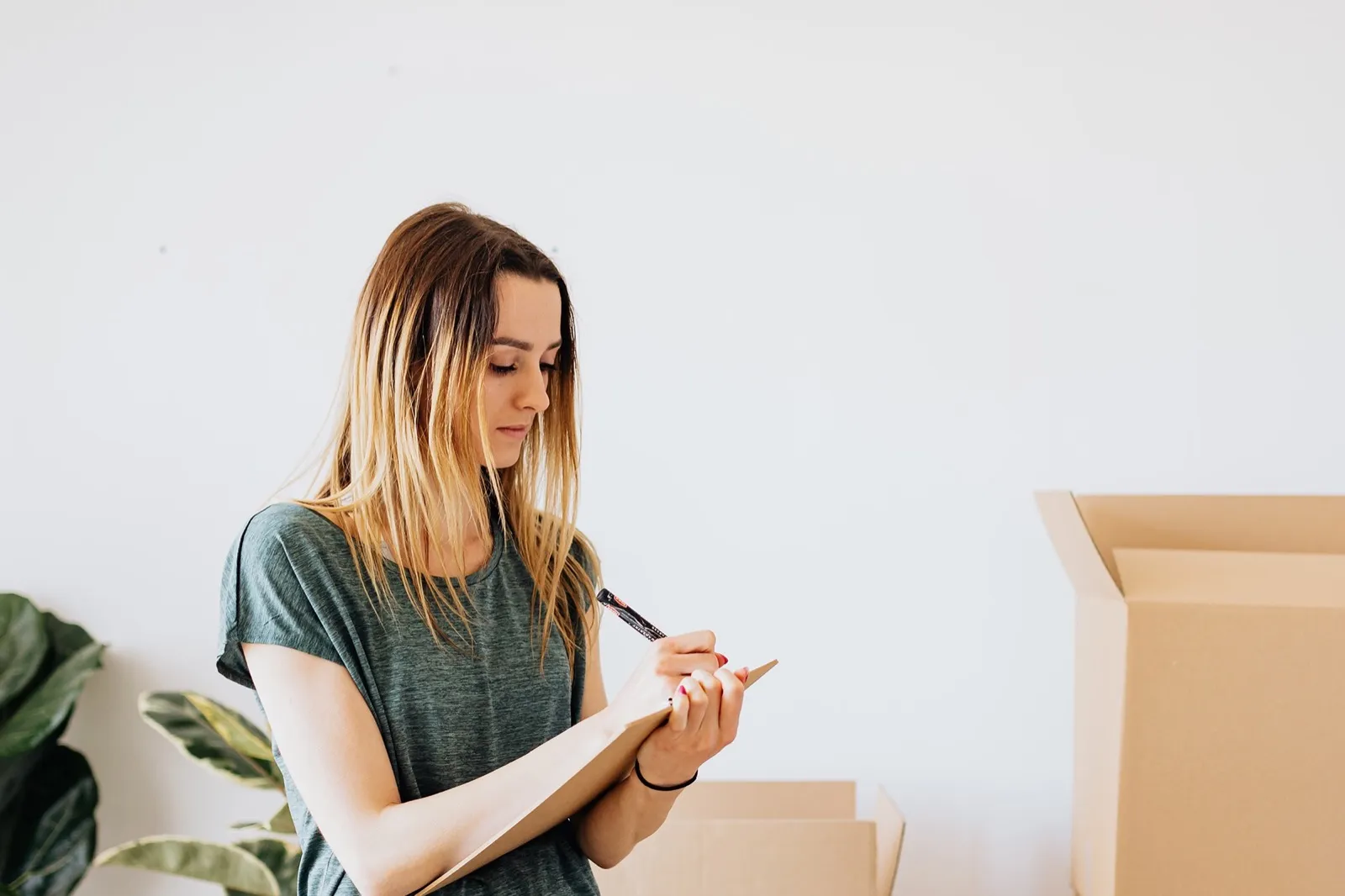 Homeowner with a clipboard making a list among packed moving boxes